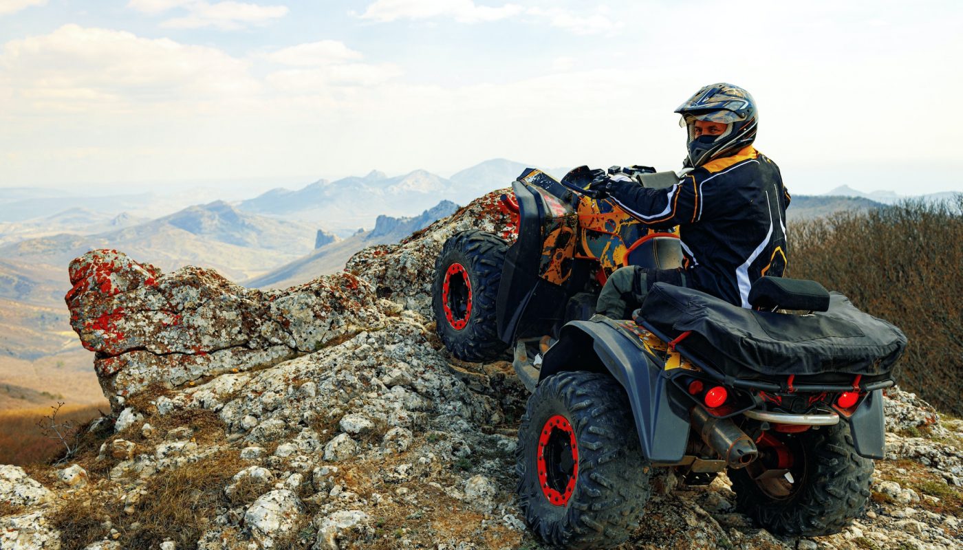 Man in helmet sitting on ATV quad bike in mountains